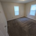 View of bedroom from entry door. Carpet, two windows, lots of electrical receptacles.