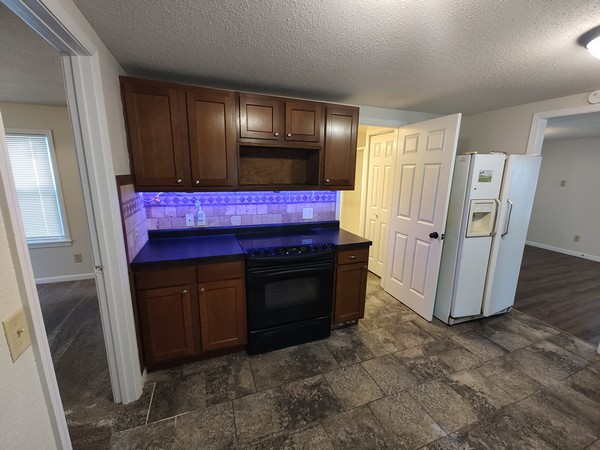 Kitchen range, fridge and door to bathroom